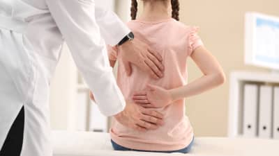 Child having spine examined.