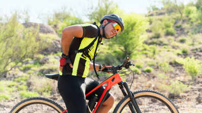 Man grabbing lower back in pain on his bicycle.