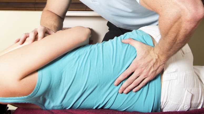 Chiropractor manipulating a patient's lumbar spine.