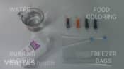 Ingredients for an ice pack including water, food coloring, rubbing alcohol, and freezer bags.