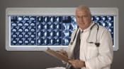 Doctor standing in front of a board of CT scans.