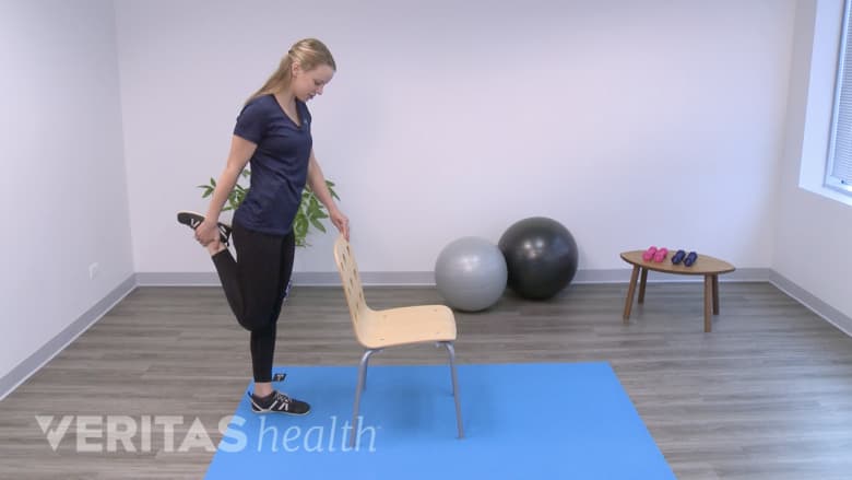 Woman performing a standing quadricep stretch, holding her right leg.