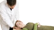 Chiropractor adjusting a supine patient's cervical spine.