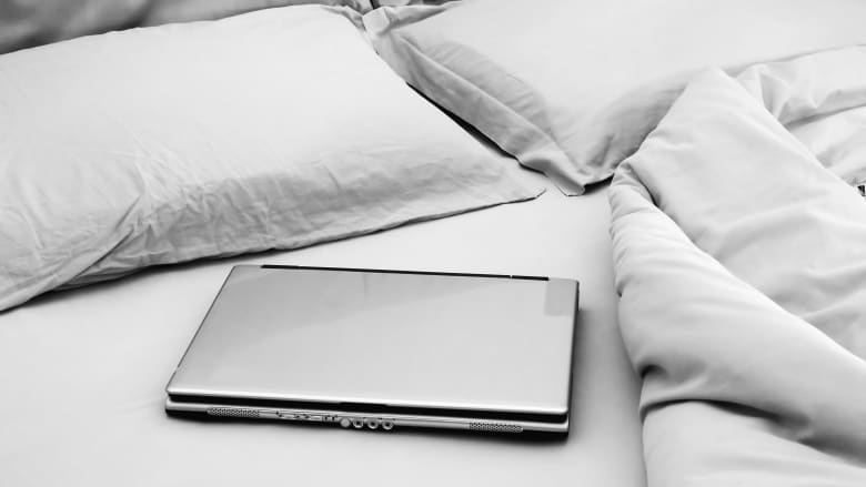 Laptop sitting on an unmade bed.