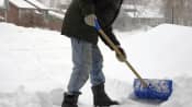 Lower body of a person shoveling snow