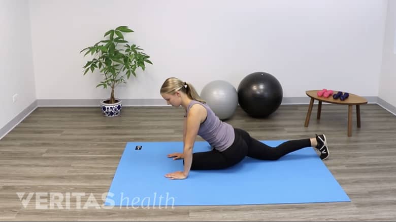 Woman performing pigeon pose yoga stretch on a yoga mat.