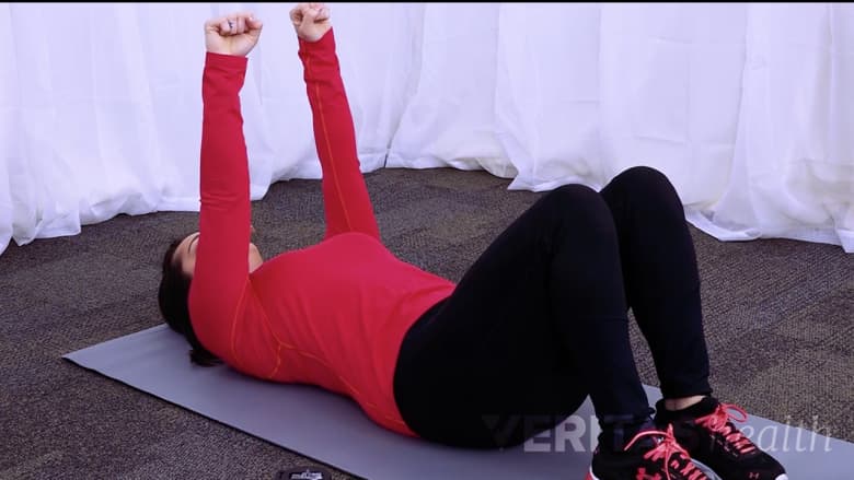 A woman lying down performing hook-lying march