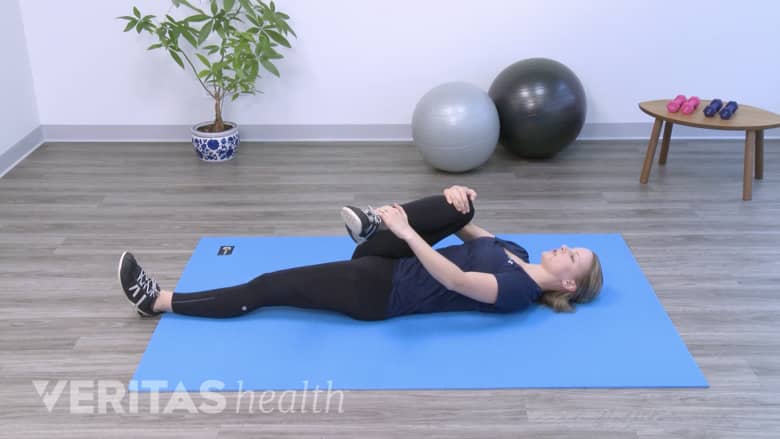 A woman performing supine piriformis stretch.