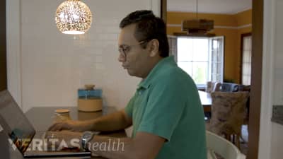 Man sitting at table in a chair to maintain good spinal posture and prevent neck pain and back pain.