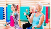 Seniors and instructor in an exercise class doing exercise ball exercises with hand weights