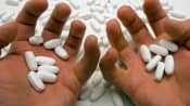 Pair of hands hold several prescription pills