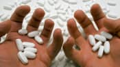 Two hands holding prescription pills.