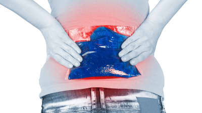 Woman applying a hot pack to her lower back