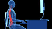 Transparent figure with a highlighted, straight spine sitting at office work station.