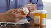 Person reading the label on a prescription pill bottle