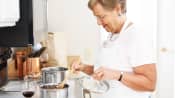 Woman with and apron stirring food in a pot on the stove
