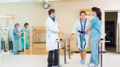 Therapists helping patient walk in a hospital after a surgery