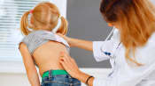 Doctor examining young patient's spine