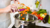 Woman cooking with vegetables at her stove.