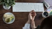 Woman's hands at a keyboard, one massaging the other