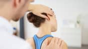 Male physical therapist massaging a young woman's neck in the medical office