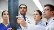 Doctors examining x-rays of patient's spine.