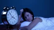 Woman staring at a clock in the middle of the night