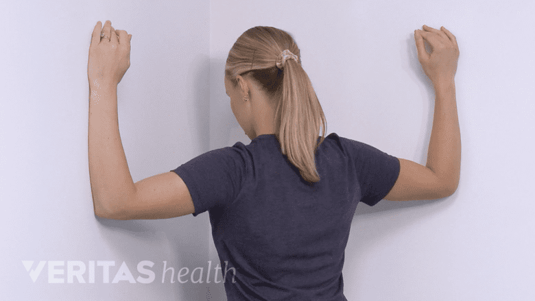 Una fisioterapeuta demostrando el estiramiento de la esquina.