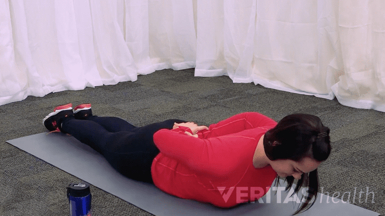Mujer haciendo el ejercicio de extensión en decúbito prono para aliviar el dolor de la ciática.